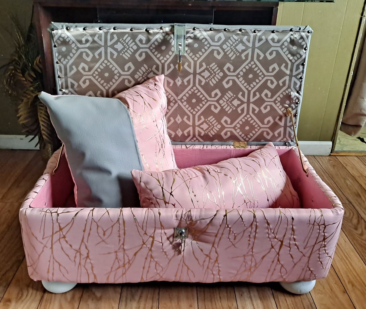 Blush upholstered custom trunk with gold details and coordinating pillows